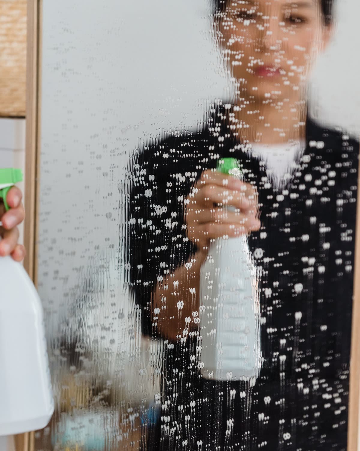 Städare sprayar och putsar en glasyta