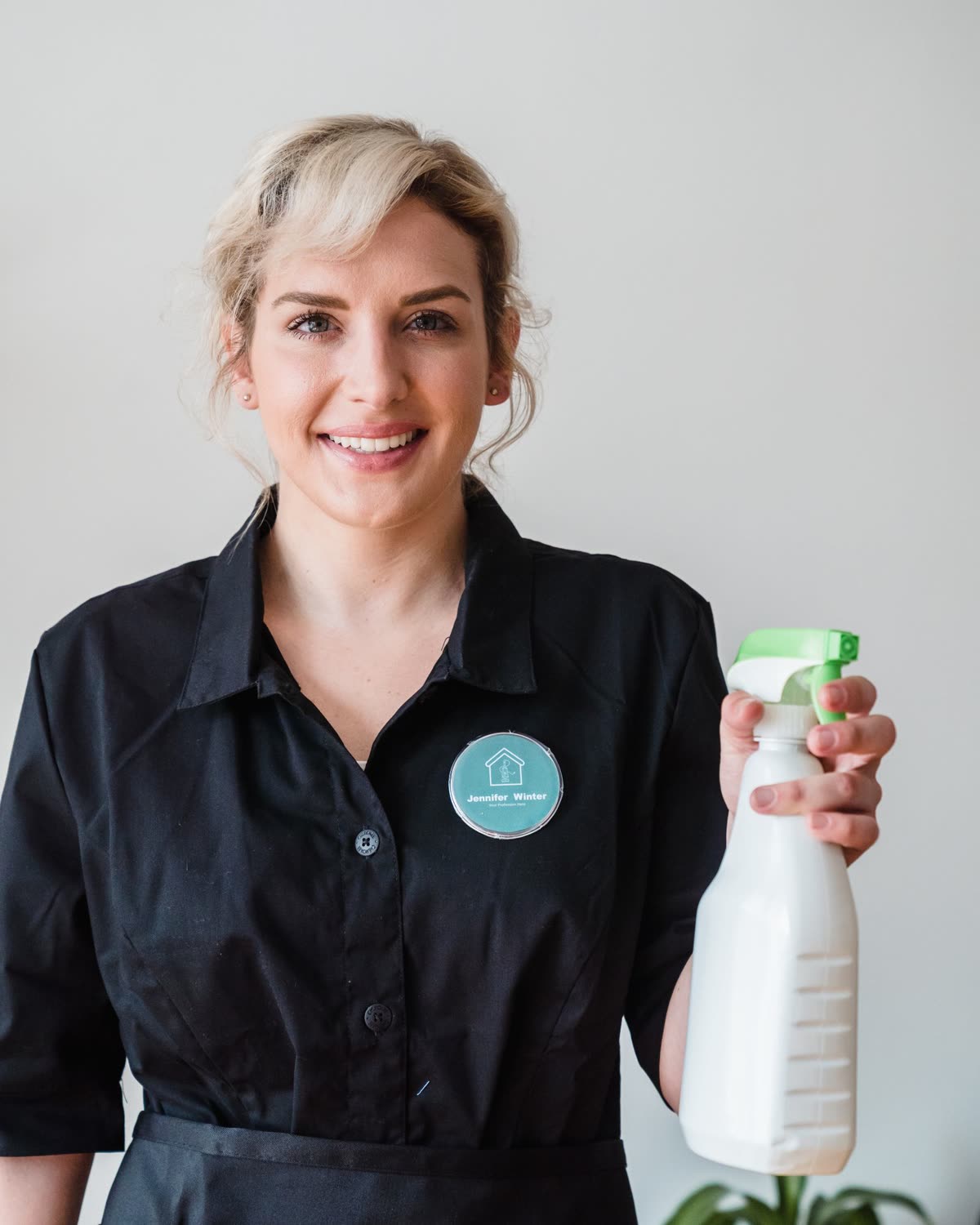 Leende städare i uniform med sprayflaska